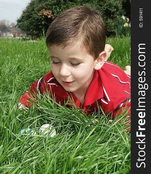 A young boy finding Easter eggs in the grass. A young boy finding Easter eggs in the grass.