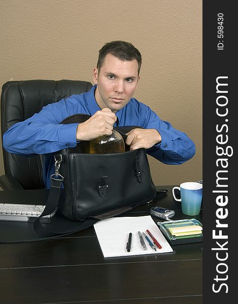Employee smuggling some whiskey at his office in the working hours, happy about being able to pass through unnoticed. Employee smuggling some whiskey at his office in the working hours, happy about being able to pass through unnoticed