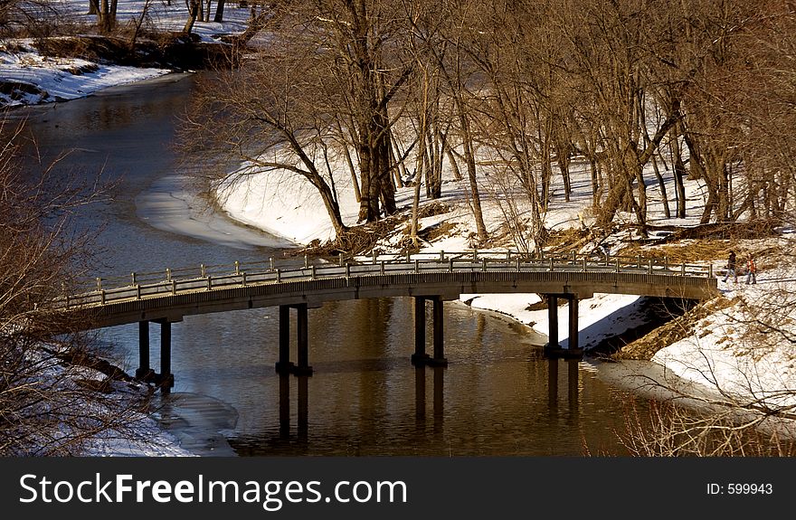 Two people on a walk through the park - about to cross a bridge. Two people on a walk through the park - about to cross a bridge