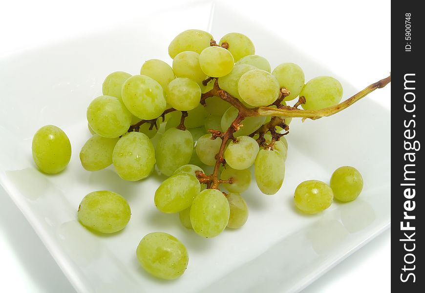 Fresh bunch of green grapes in white bowl and isolated on white background