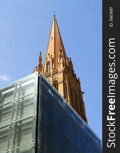 Church tower with modern building against blue sky in Melbourne