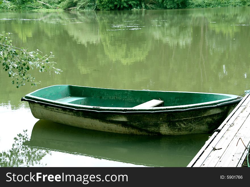 Abandoned green boat at the river, peacefull landscape.