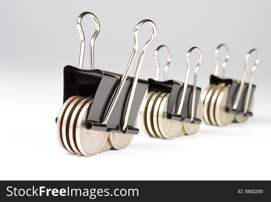 Coins clamped by a paper clip on a white background.