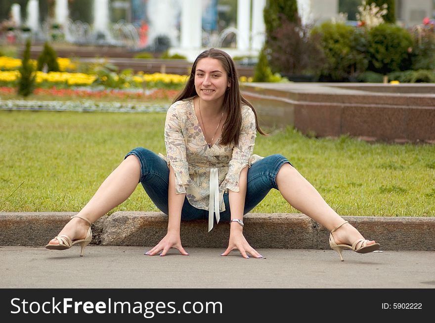 Attractive girl is sitting on the border in a city park. Attractive girl is sitting on the border in a city park