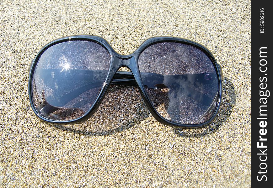 Sunglasses on a background of sand