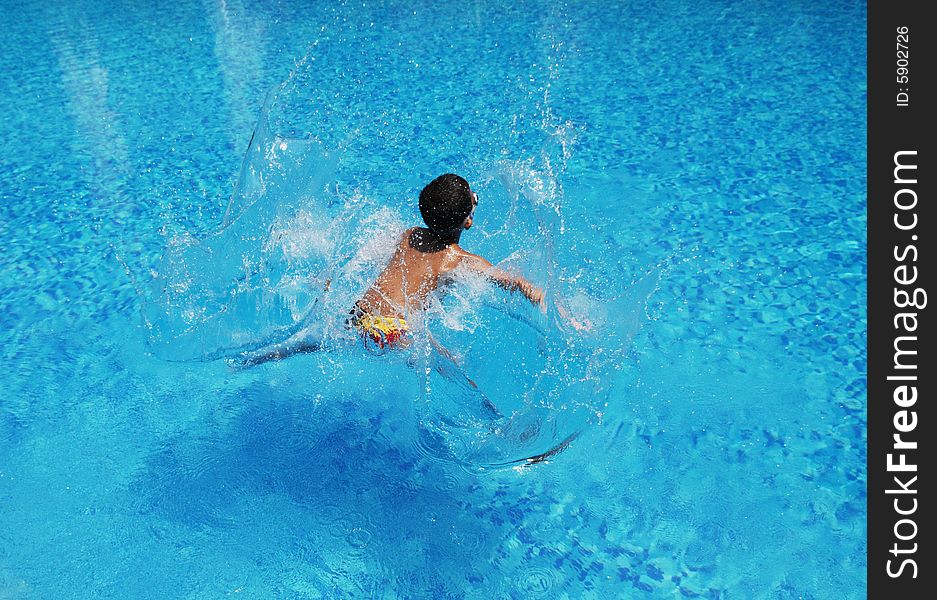 A boy jumps into the blue and clear water splashing big waves. A boy jumps into the blue and clear water splashing big waves.