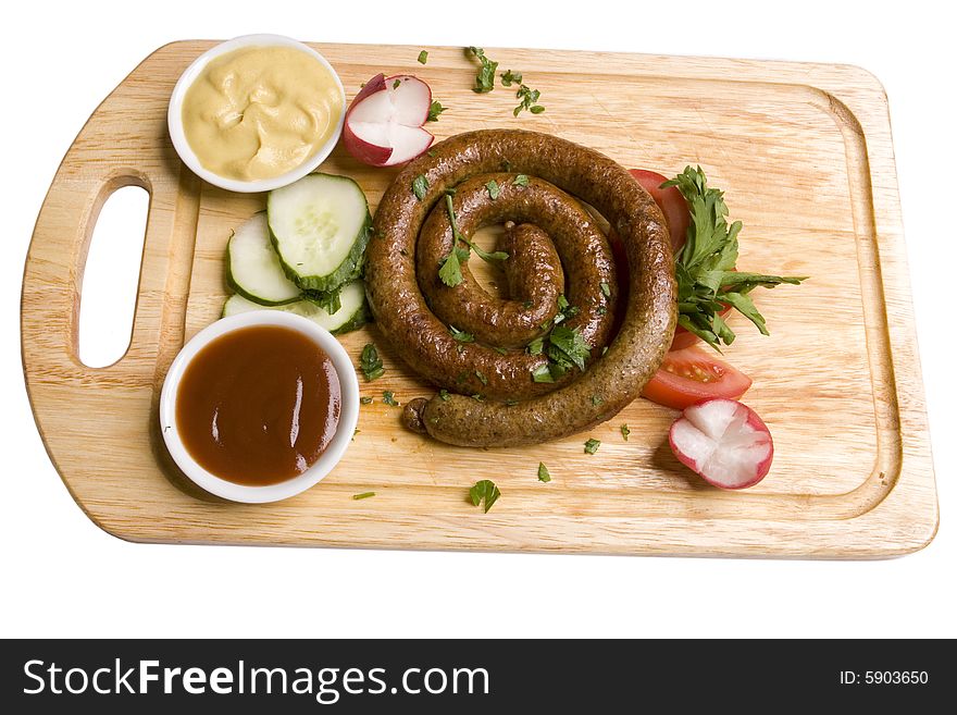 Twisted frankfurter with sauces and vegetables on wooden board on white ground