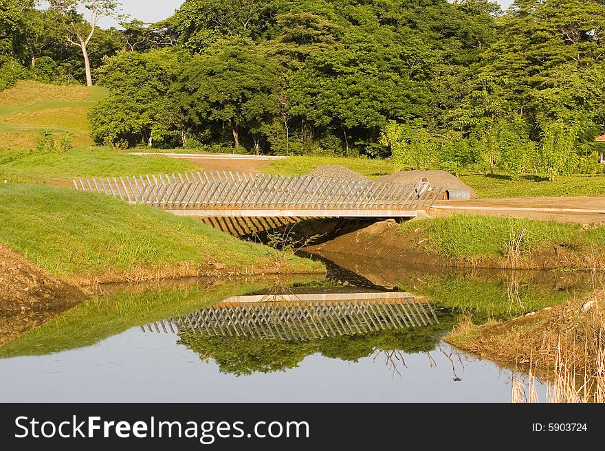 A lattice wood bridge over a lake with reflections in the water. A lattice wood bridge over a lake with reflections in the water