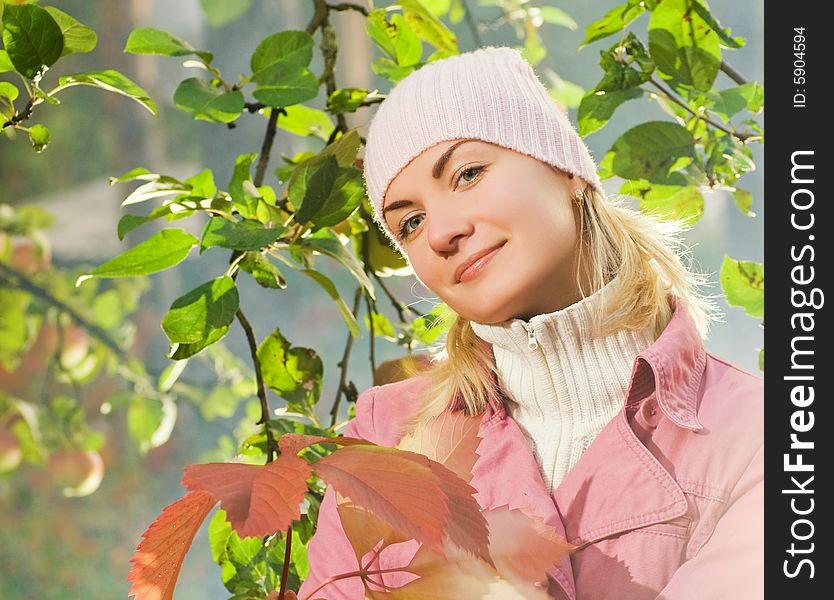 Beautiful girl with autumn leaves near the apple tree