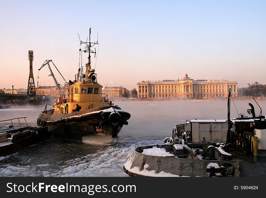 A small yellow river ice breaker near an embankment. A small yellow river ice breaker near an embankment