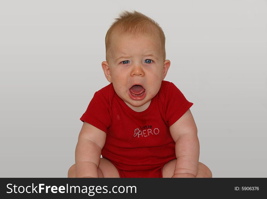 Newborn baby sitting and howling in a red shirt. Newborn baby sitting and howling in a red shirt.