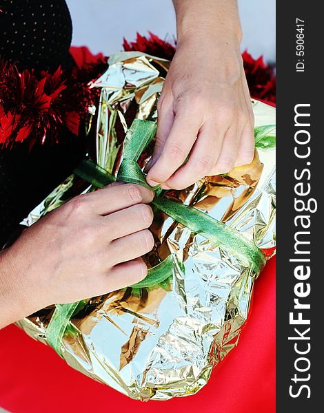 Close-up of a woman unwrapping a Christmas gift.