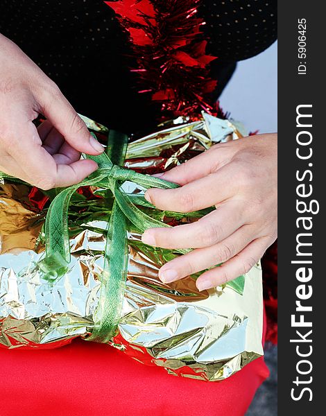 Close-up of a woman unwrapping a Christmas gift. Close-up of a woman unwrapping a Christmas gift.