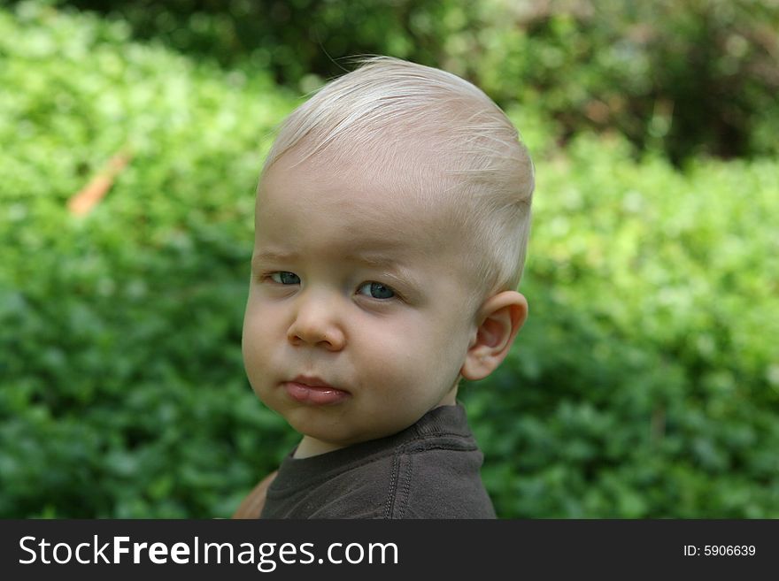 Child toddler with blond hair is staring contemplative at the camera. Child toddler with blond hair is staring contemplative at the camera.