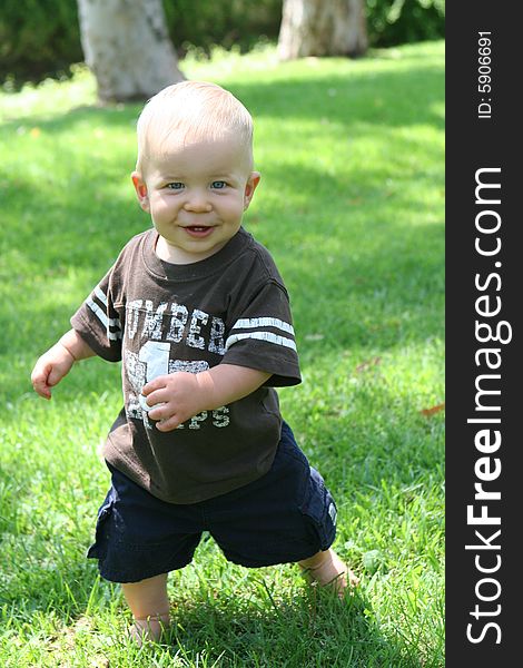 Child toddler is standing on grass in an amimated motion. Child toddler is standing on grass in an amimated motion