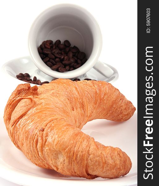 Croissant and cup with coffee beans