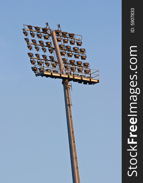 Stadium lights before sunset against sky