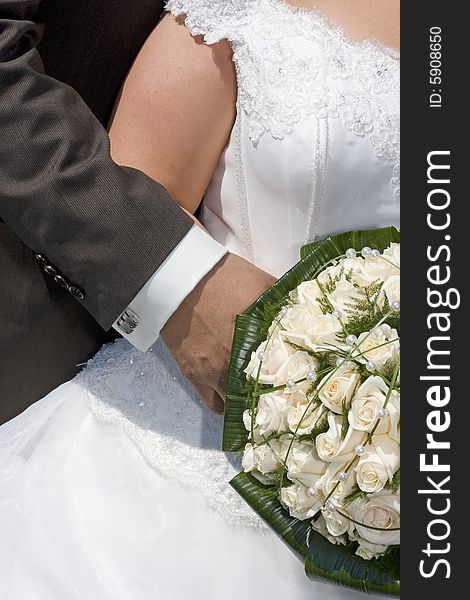 Bride and groom holding bridal bouquet with white roses