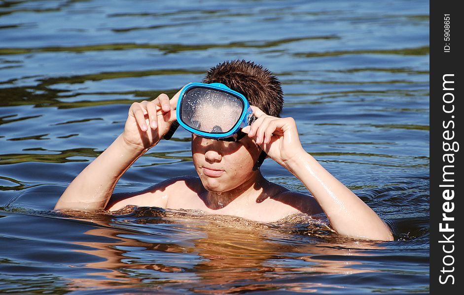 The boy putting on his diving mask before swimming. The boy putting on his diving mask before swimming.