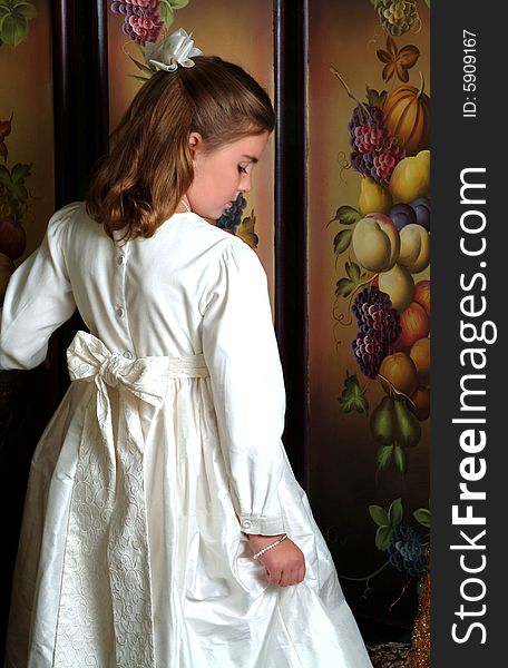 Back of winter white dress of school aged girl with solemn expression