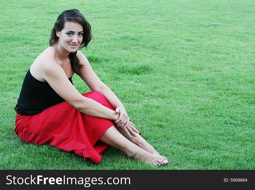 Portrait of a beautiful woman sitting on the grass.