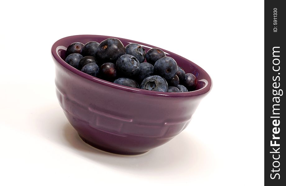Blueberries in a purple bowl on a white background