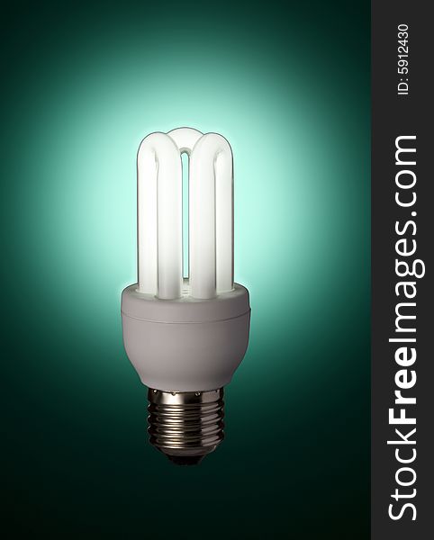 Glowing energy saving florescent light bulb with a green lightbulb. Glowing energy saving florescent light bulb with a green lightbulb
