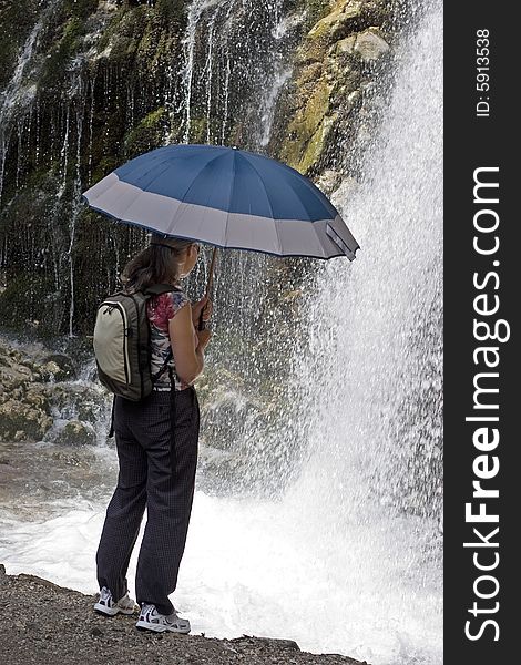 Tourist woman looking at a mountain waterfall. Tourist woman looking at a mountain waterfall