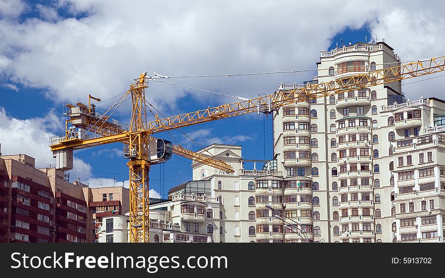 The building crane on a background of modern houses. The building crane on a background of modern houses