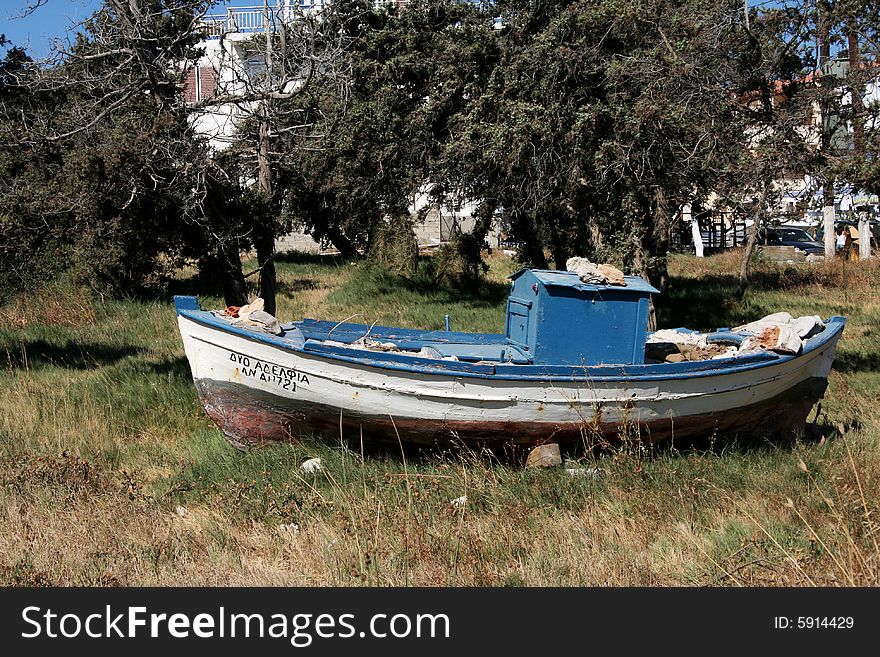 An old fishing boat not used anymore thrown on the grass. An old fishing boat not used anymore thrown on the grass