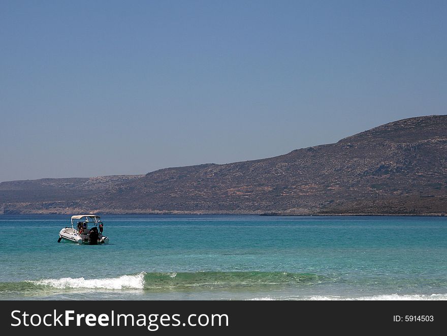 A motor boat sailing towards a sandy beach. A motor boat sailing towards a sandy beach