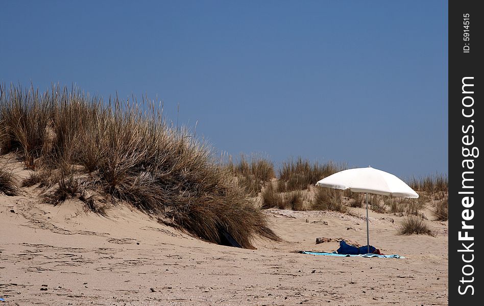 A lonely white umbrella on a sandy beach of a Greek island. A lonely white umbrella on a sandy beach of a Greek island