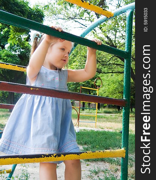 The girl on a children's playground plays on gymnastic ladders. The girl on a children's playground plays on gymnastic ladders