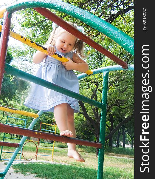 The girl on a children's playground plays on gymnastic ladders. The girl on a children's playground plays on gymnastic ladders