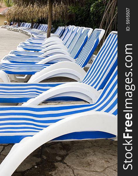 Blue and White striped lounge chairs along a tropical pool. Blue and White striped lounge chairs along a tropical pool