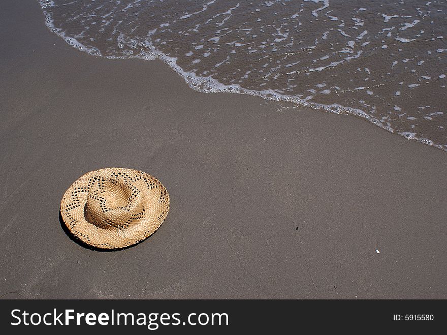 In this photo is situated a hat at the send, and surf.