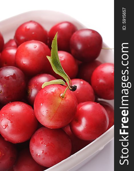 Red cherry-plum in the white plastic bowl. Narrow depth of field. Red cherry-plum in the white plastic bowl. Narrow depth of field.