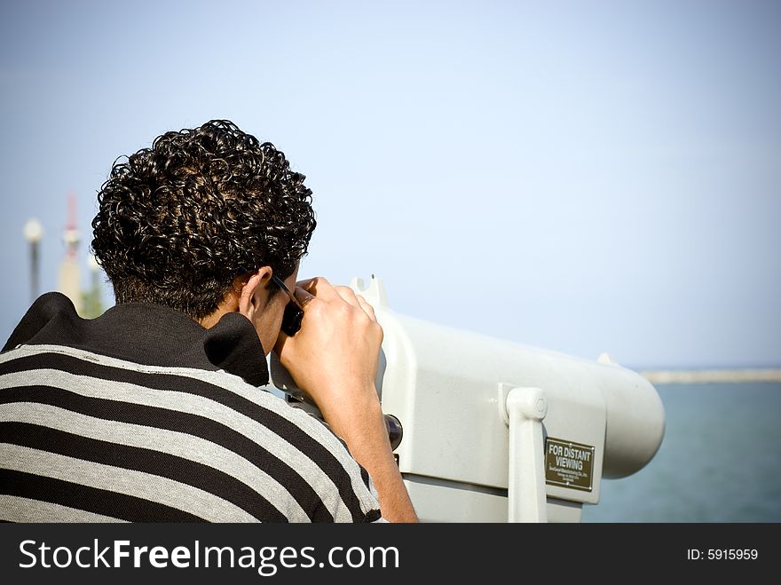 Young man looking through a viewing scope. Young man looking through a viewing scope