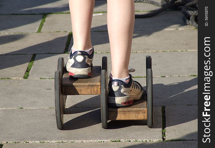 The boy goes for a drive on asphalt on old wooden rollers