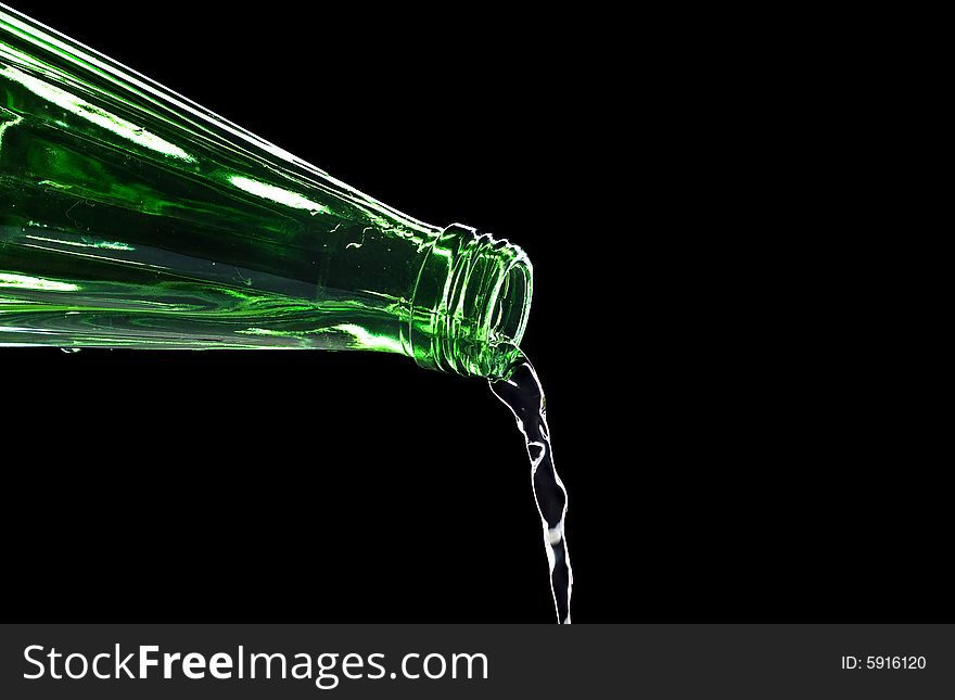 Flowing water from bottle isolated on black