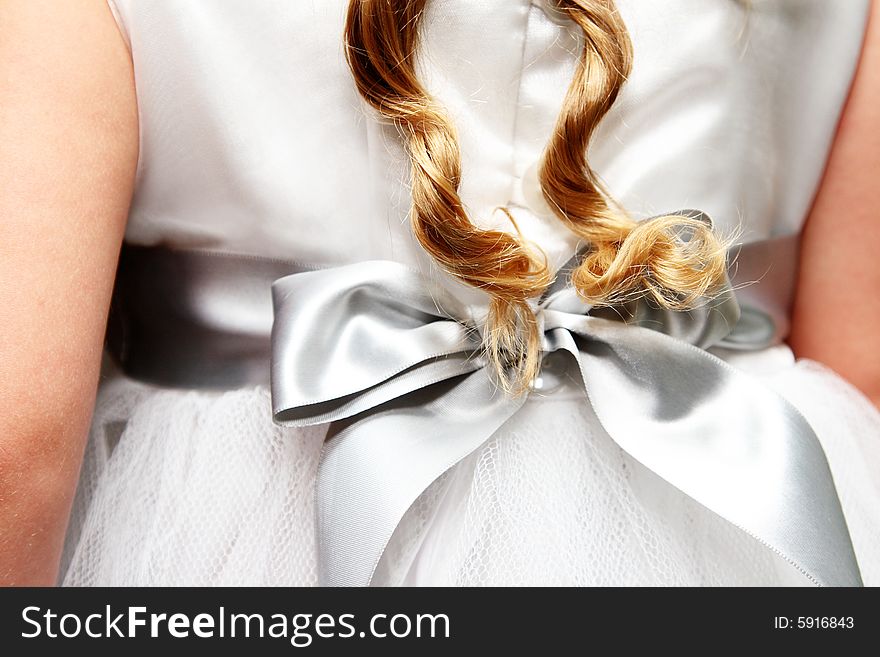 Twirled locks of golden hair against a flower-girl dress