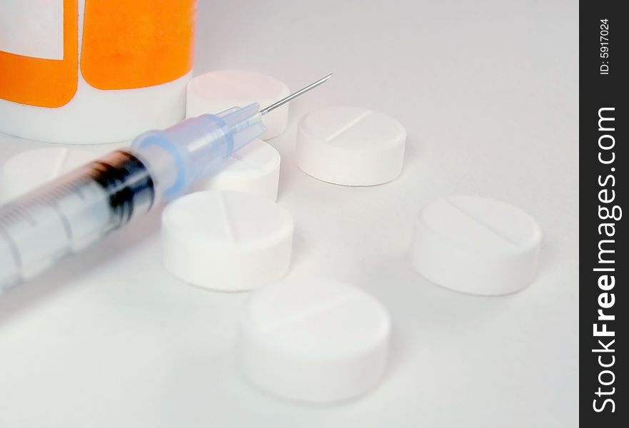 Tablets a syringe and a drug container on a white surface. Tablets a syringe and a drug container on a white surface
