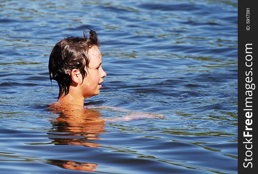 The profile of the boy swimming deep in a lake. The profile of the boy swimming deep in a lake.