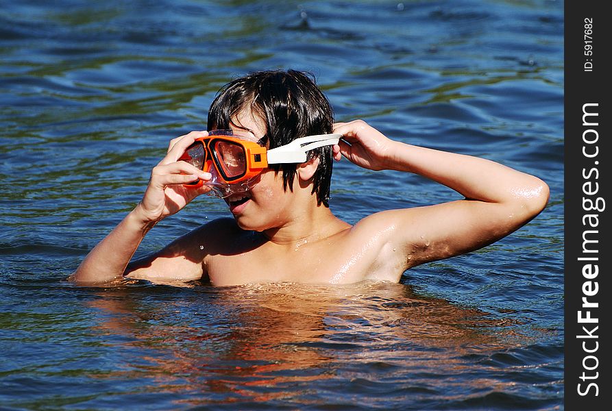 The boy putting on his diving mask to dive in a small lake. The boy putting on his diving mask to dive in a small lake.