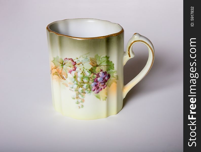 A china cup with grapes and leaves on it