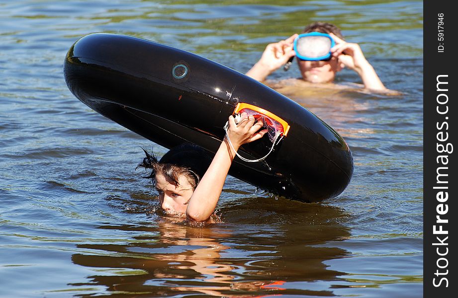 The boy carrying his tube just above the water in a small lake. The boy carrying his tube just above the water in a small lake.