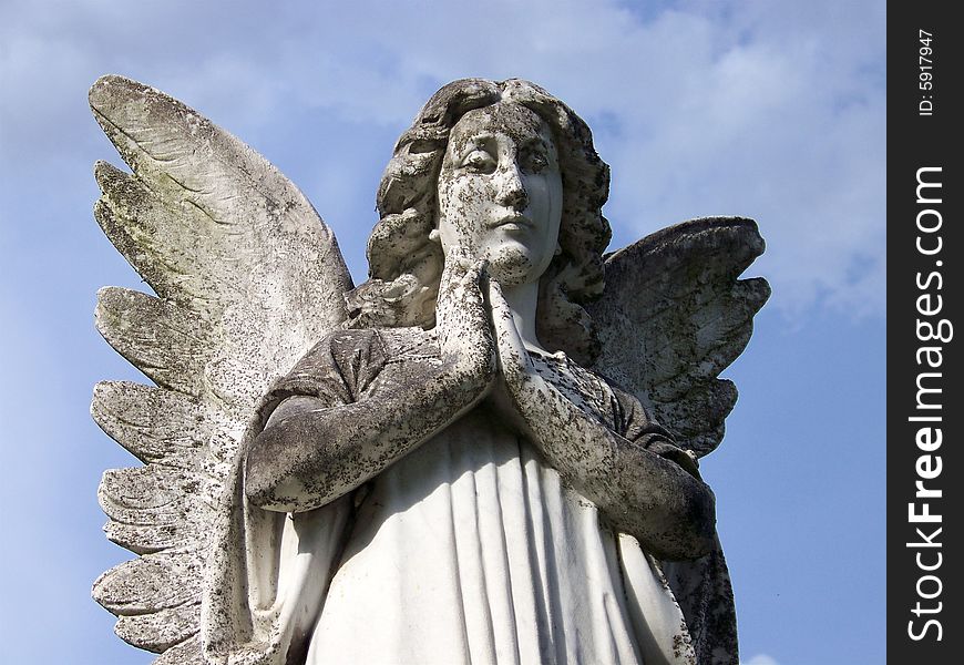 A praying angel is weathered by time and is still beautiful and peaceful to look at.