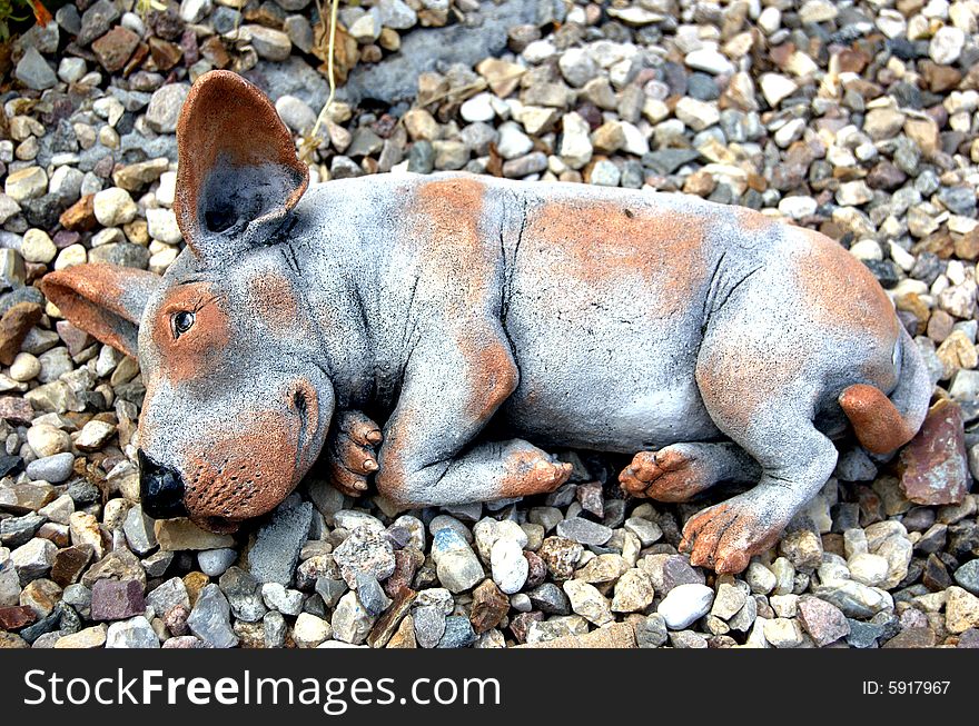 Toy ceramic dog lying on stones. Toy ceramic dog lying on stones