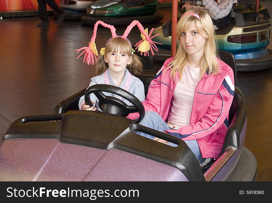 Two girls in an amusement park go by the small car