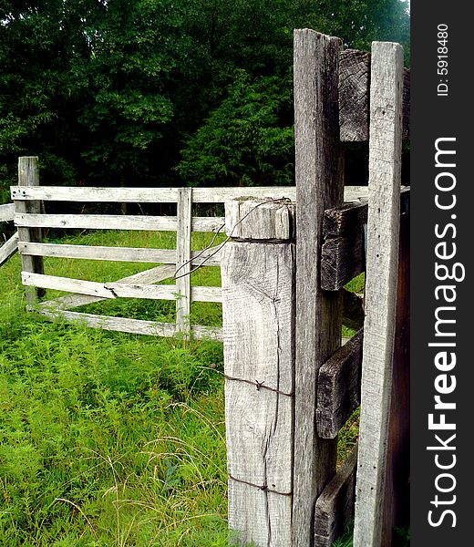 A weathered gray-wood farm fence wrapped with barbed wire. A weathered gray-wood farm fence wrapped with barbed wire